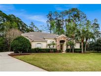 Spacious one-story home with a sprawling lawn, mature landscaping, and a welcoming stone entrance at 943 Elm Harbor Ct, Lake Mary, FL 32746