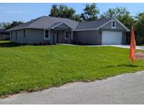 Charming single-story home featuring a lush green lawn and attached two-car garage, ideal for Gathering living at 8749 Se 159Th Ln, Summerfield, FL 34491