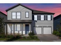 Two-story home featuring a two-car garage, blue front door, and manicured landscaping at 11218 Pixie Mandarin Ct, Winter Garden, FL 34787