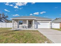 Newly constructed home with a gray exterior, white garage door, and landscaped yard at 1460 3Rd Ave, Deland, FL 32724