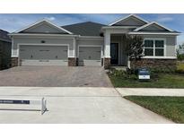Charming single-Gathering home with a three-car garage and a beautifully paved driveway and stone detailing at 5379 Park Guell St, St Cloud, FL 34771
