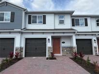 Charming two-story townhome featuring a well-manicured brick entryway and a convenient attached garage at 5086 Rain Shadow Dr, St Cloud, FL 34772