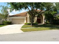 Charming single-story home with a well-manicured lawn, mature trees, and a two-car garage at 519 Lakescape Ct, Orlando, FL 32828