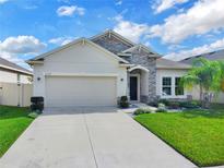 Charming single-story home with a stone facade, well-manicured lawn, and a two-car garage on a sunny day at 5364 Ragusa Loop, St Cloud, FL 34771