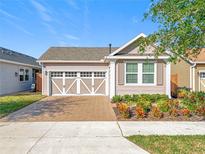 Charming single-Gathering home featuring a decorative garage door, tidy landscaping, and a brick driveway at 349 Alcove Dr, Groveland, FL 34736