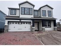 Two-story home with white siding, black accents, and a brick driveway at 5069 Rain Shadow Dr, Saint Cloud, FL 34772