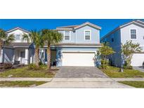 Charming two-story home with a two car garage, tropical landscaping, and a brick paver driveway at 7400 Oakmoss Loop, Davenport, FL 33837