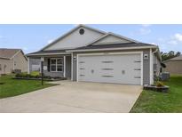 Charming single-story home featuring a two-car garage, well-maintained lawn, and neutral gray siding at 4694 Monica St, The Villages, FL 32163