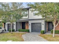 Modern townhome featuring a gray facade, black garage door and a neatly landscaped walkway leading to the front entrance at 4457 Le Reve Ct, Kissimmee, FL 34746