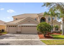 Two-story house with three-car garage, landscaping, and a brick paved driveway at 3814 Golden Feather Way, Kissimmee, FL 34746