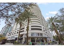 Modern high-rise building with palm trees and street-level businesses at 100 S Eola Dr # 608, Orlando, FL 32801