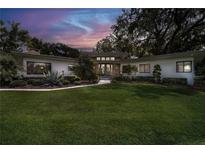 Charming single-story home featuring a sprawling lawn, manicured landscaping, and a stone accented entryway at 12550 Lakeshore Dr, Clermont, FL 34711