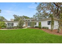 Beautifully landscaped front yard with lush green lawn and mature trees at 12550 Lakeshore Dr, Clermont, FL 34711