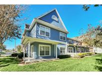 Charming blue two-story townhome featuring a welcoming front porch, bright windows, and a well-manicured lawn at 2203 San Vittorino Cir # 102, Kissimmee, FL 34741