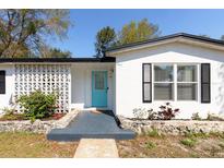 Charming home featuring a decorative brick wall, an inviting turquoise front door, and freshly painted white exterior at 1311 Hartley Ave, Deltona, FL 32725