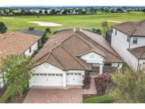 Expansive home featuring a clay tile roof, three-car garage, brick driveway and landscaping, on a golf course at 8914 Dove Valley Way, Davenport, FL 33896