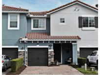 Two-story townhome with dark brown garage doors and a landscaped front yard at 1720 Garden Sage Dr, Oviedo, FL 32765