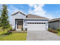 Charming single-story home featuring a paved driveway, manicured lawn, and attached two-car garage at 9097 Wildlight Trl, Wildwood, FL 34785