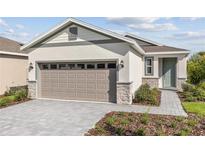 Charming single-Gathering home with a two-car garage, neutral stucco, stone accents, and a well-manicured lawn at 9116 Wildlight Trl, Wildwood, FL 34785