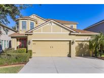 Two-story house with a beige exterior, three-car garage, and landscaping at 1426 Plumgrass Cir, Ocoee, FL 34761