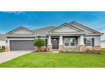 Charming single-story home with a two-car garage and a covered front porch, set against a blue sky at 2982 Arranmore Dr, Ormond Beach, FL 32174