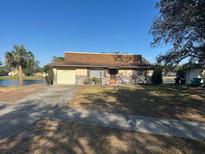 Ranch-style home with attached garage and a large yard, located on a lake at 4518 Watch Hill Rd, Orlando, FL 32808