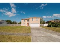 Inviting two-story home featuring a large front yard and an attached two car garage at 2824 Corrigan Dr, Deltona, FL 32738