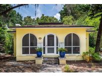 Charming yellow home featuring arched windows and a welcoming front entrance with potted plants at 786 Antonette Ave, Winter Park, FL 32789