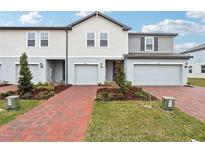 Two-story townhome with gray siding, two-car garage, and landscaped front yard at 16332 Happy Eagle Dr, Clermont, FL 34714