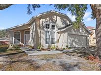 Tan house with white garage door and landscaping at 230 Bay Meadow Dr, Kissimmee, FL 34746