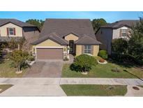 Two-story house with a brown roof, beige walls, and a paved driveway at 2532 Civitas Pl, Casselberry, FL 32707