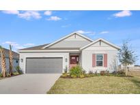 Single-story home with gray siding, brick red door, matching shutters, manicured lawn, and a two-car garage at 4723 Coral Harbour Rd, Kissimmee, FL 34758