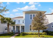 Charming two-story home with a blue exterior, covered porch, manicured lawn and beautiful landscaping at 8279 Nemours Pkwy, Orlando, FL 32827