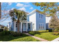 Inviting two-story home featuring a covered porch, well-maintained lawn, and lush landscaping at 8279 Nemours Pkwy, Orlando, FL 32827