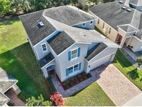 Charming two-story home with a well-manicured lawn, brick driveway, and bright blue shutters at 3207 Stratton Cir, Kissimmee, FL 34744