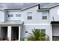 Contemporary townhome featuring clean lines, neutral tones and stylish architectural details, plus a small palm tree at 8943 Cabot Cliffs Dr, Davenport, FL 33896