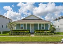 Charming single-story home with a blue exterior, well-manicured landscaping and a bright sunny sky at 15542 Sunquat Dr, Winter Garden, FL 34787