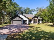 Charming two-car garage home featuring a brick driveway and a beautifully manicured lawn at 347 Mission Rd, Oviedo, FL 32765