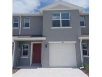 Two-story home with gray siding, red door, a white garage door, and well-maintained front yard at 545 Zinfandel Dr, Holly Hill, FL 32117