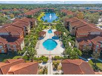 A bird's-eye view of a beautiful community with a pool, palm trees, lush landscaping, and a serene lake with a fountain at 5578 Metrowest Blvd # 101, Orlando, FL 32811