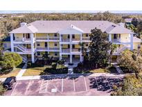 Three-story yellow condo building featuring multiple balconies and lush landscaping at 411 Lucaya Loop # 411, Davenport, FL 33897
