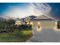 Tan three-car garage house with palm trees and well-manicured lawn at 3597 Valleybrook Way, The Villages, FL 32163