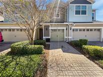 Charming townhome featuring a brick driveway, manicured shrubs and a single-car garage at 1106 Presidential Ln, Apopka, FL 32703