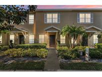Inviting townhome featuring manicured landscaping, a walkway to the entrance, and a charming covered porch at 13228 Daniels Landing Cir, Winter Garden, FL 34787