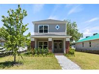 Charming two-story home featuring gray siding, brick accents, and a welcoming covered front porch at 813 S Locust Ave, Sanford, FL 32771