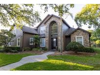 Charming two-story home featuring a stone facade, arched entryway, and manicured lawn at 1912 Westover Reserve Blvd, Windermere, FL 34786