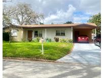 Charming single-story brick home with a well-maintained lawn and covered carport with 2 cars parked in the driveway at 1222 San Luis Dr, Orlando, FL 32807