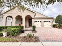 Inviting home with landscaped front yard, brick driveway, and charming arched entryway and two-car garage at 15531 Waterleigh Cove Dr, Winter Garden, FL 34787