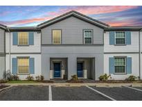 Inviting townhome exterior with blue shutters and well-maintained landscaping at 7420 Oakmoss Loop, Davenport, FL 33837