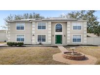 Two-story home featuring a green door, trimmed windows, solar panels, and front yard landscaping at 800 Daybreak Dr, Fruitland Park, FL 34731